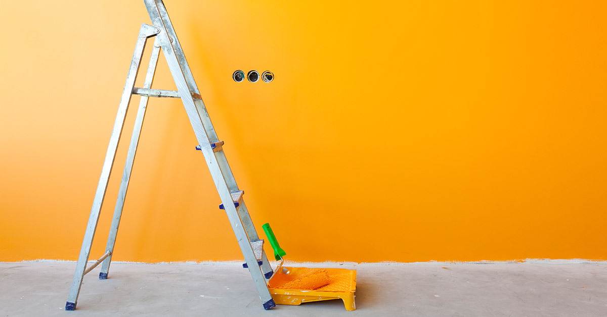 Vorbereitung für Renovierungsarbeiten: Metallleiter steht an einer orangenen Wand.