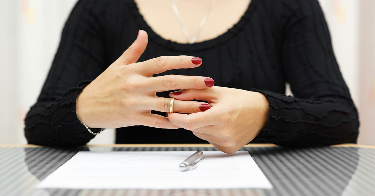 Eine Frau die Ihren Ehering vom Finger zieht - Scheidungsimmobilie